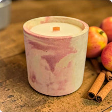Load image into Gallery viewer, Candle in a pink and white container on a wooden surface with apples and cinnamon sticks.