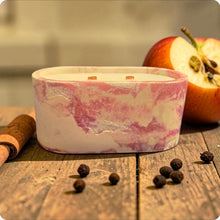Load image into Gallery viewer, Marble-patterned candle in a white holder on a wooden surface with an apple and cinnamon sticks.