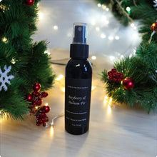 Load image into Gallery viewer, A black spray bottle labeled 'Bayberry of Balsam Fir' placed on a surface with Christmas decorations in the background, including lights and presents.