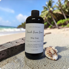 Load image into Gallery viewer, Bottle of 'Beach Bum Bum' mop soap on a beach with a shell and driftwood.