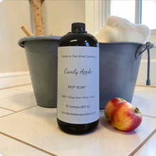 Load image into Gallery viewer, Bottle of 'Candy Apple' mop soap on a tiled floor with an apple and buckets in the background.