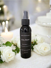 Load image into Gallery viewer, A black spray bottle labeled 'Eros Amore' placed among white roses, with a blurred background suggesting a sophisticated setting.