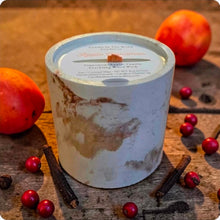 Load image into Gallery viewer, Candle in a marbled concrete container with a rustic design on a wooden surface with apples and spices.
