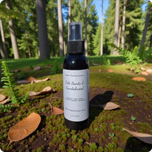 Load image into Gallery viewer, Bottle of Palo Santo & Sandalwood spray on a forest floor with trees in the background