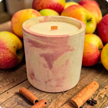 Load image into Gallery viewer, Candle in a decorative container with apples and cinnamon sticks on a wooden surface
