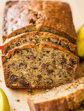 Load image into Gallery viewer, Sliced banana bread with raisins on a wooden cutting board
