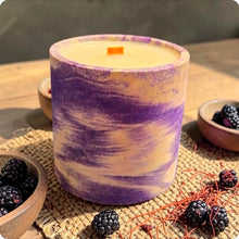 Load image into Gallery viewer, Concrete candle with purple  marbled on a woven mat with blackberries and saffron.
