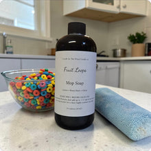 Load image into Gallery viewer, Bottle of soap labeled 'Fruit Loops Mop Soap' on a kitchen counter with cereal and a towel.
