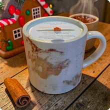 Load image into Gallery viewer, White mug with a label on a wooden surface with a cinnamon stick and gingerbread house in the background
