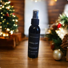Load image into Gallery viewer, A black spray bottle labeled 'Holiday Spice' positioned on a wooden surface with a festive background featuring Christmas decorations.
