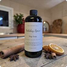 Load image into Gallery viewer, Bottle of Holiday Spice Mop Soap on a wooden surface with spices and oranges.
