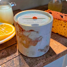 Load image into Gallery viewer, Marbled concrete candle on wooden surface with lemon slice and lemon pound cake.
