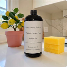 Load image into Gallery viewer, Mop soap bottle labeled 'Lemon Pound Cake' with a sponge and potted plant on a kitchen counter.
