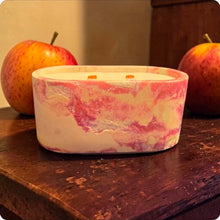 Load image into Gallery viewer, Marbled pink concrete candle on a wooden surface with apples in the background
