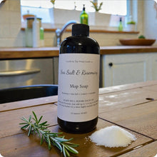 Load image into Gallery viewer, Bottle of Sea Salt &amp; Rosemary Mop Soap on a wooden surface with rosemary and salt crystals.

