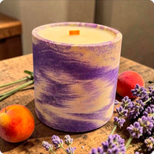 Load image into Gallery viewer, Concrete candle with purple and white pattern on a wooden surface with apricots and lavender.
