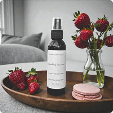 Load image into Gallery viewer, Bottle of strawberry macaron-scented room spray on a wooden tray with strawberries and macarons.
