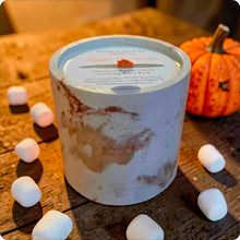 Load image into Gallery viewer, Candle in decorative concrete on a wooden surface with pumpkins and marshmallows.
